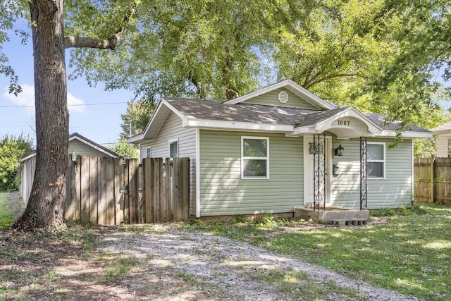 bungalow-style house featuring roof with shingles and fence