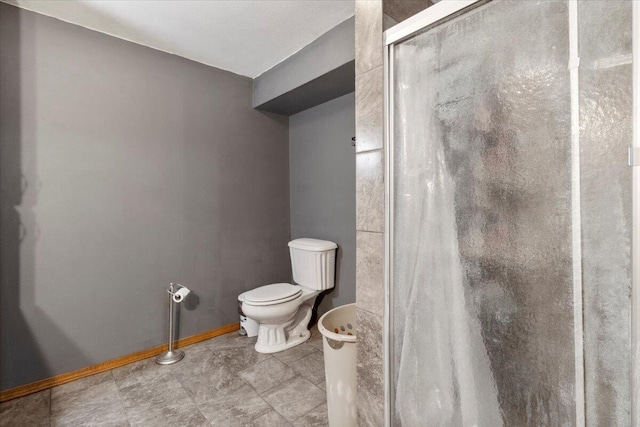 bathroom featuring a stall shower, toilet, and baseboards