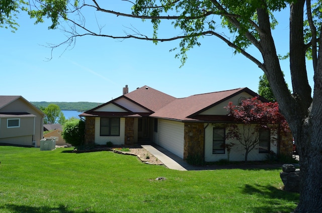 ranch-style house featuring a chimney, central AC unit, stone siding, and a front yard