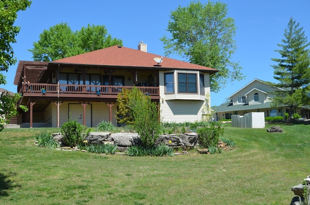 back of house with a wooden deck, a lawn, and a chimney