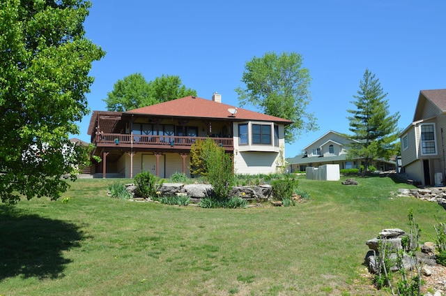 rear view of property with a lawn, a chimney, and a deck