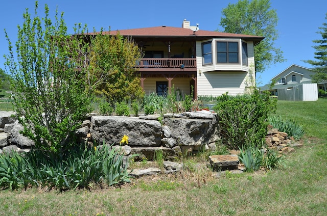 back of property featuring a chimney and a yard