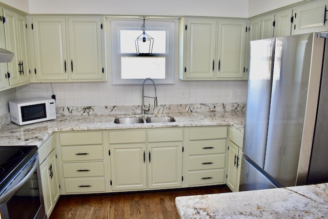 kitchen with tasteful backsplash, dark wood-type flooring, light stone countertops, appliances with stainless steel finishes, and a sink