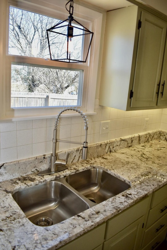 details with a sink, decorative backsplash, light stone countertops, and green cabinetry