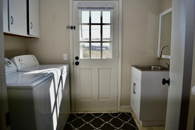 clothes washing area with a sink, cabinet space, and washer and dryer