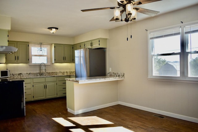 kitchen featuring white microwave, visible vents, freestanding refrigerator, and green cabinetry