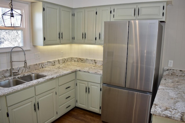 kitchen with decorative backsplash, dark wood finished floors, freestanding refrigerator, and a sink