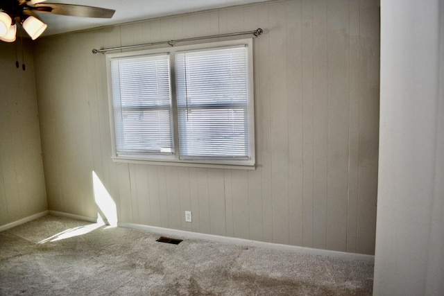 carpeted spare room with a ceiling fan, visible vents, and baseboards