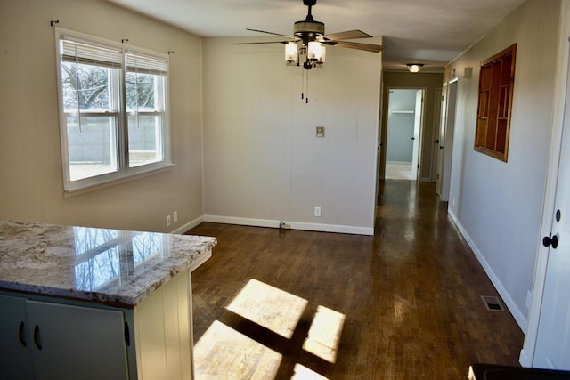 unfurnished dining area featuring visible vents, baseboards, dark wood-type flooring, and a ceiling fan