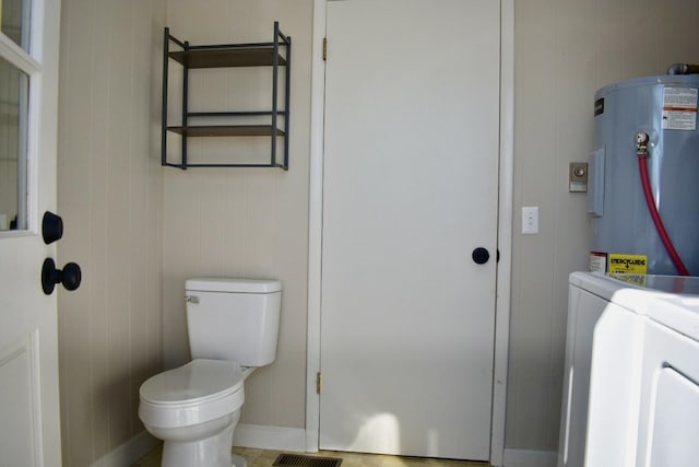 bathroom featuring baseboards, toilet, and water heater