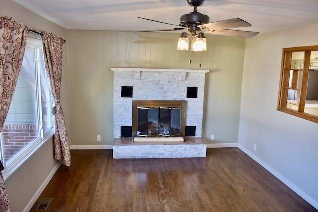 unfurnished living room featuring a ceiling fan, wood finished floors, visible vents, baseboards, and a brick fireplace