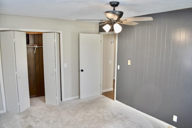 unfurnished bedroom featuring a closet, light carpet, and wood walls