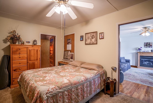 2457 County Road 1770, West Plains, MO 65775 - bedroom with wood finished floors, ceiling fan, and a glass covered fireplace