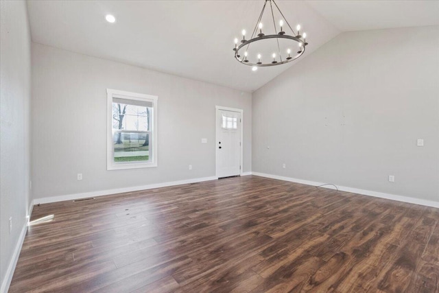 spare room with baseboards, lofted ceiling, an inviting chandelier, and dark wood-style flooring