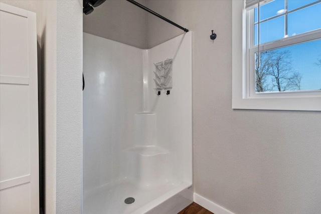 bathroom featuring a shower and baseboards