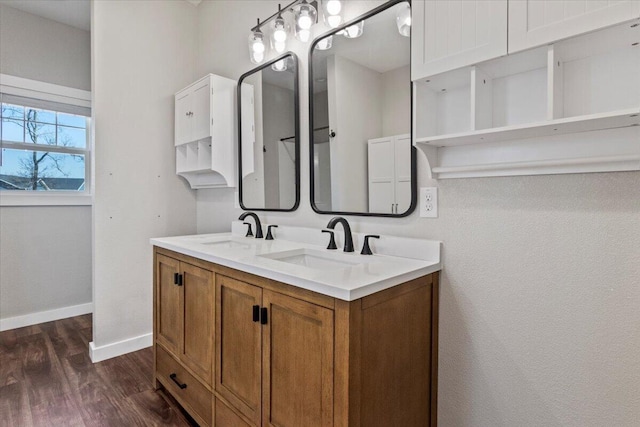 full bath with a sink, baseboards, wood finished floors, and double vanity