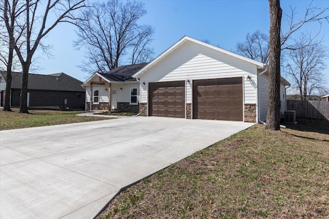 ranch-style house featuring a front yard, fence, concrete driveway, stone siding, and central air condition unit