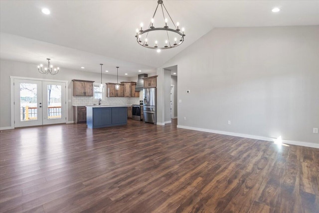 unfurnished living room featuring a notable chandelier, dark wood finished floors, recessed lighting, baseboards, and vaulted ceiling