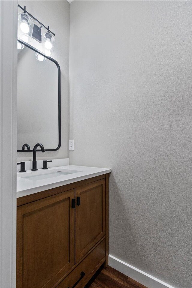 bathroom featuring vanity, wood finished floors, baseboards, and a textured wall