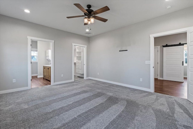 unfurnished bedroom featuring a spacious closet, baseboards, carpet flooring, recessed lighting, and ensuite bath