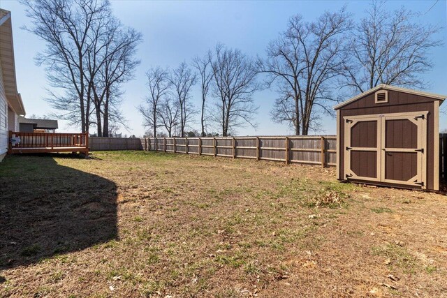 view of yard featuring an outbuilding, a deck, a storage shed, and a fenced backyard