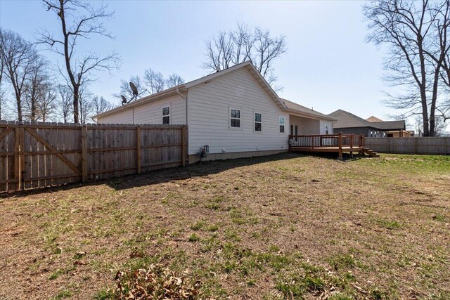 back of property with a yard, a deck, and a fenced backyard