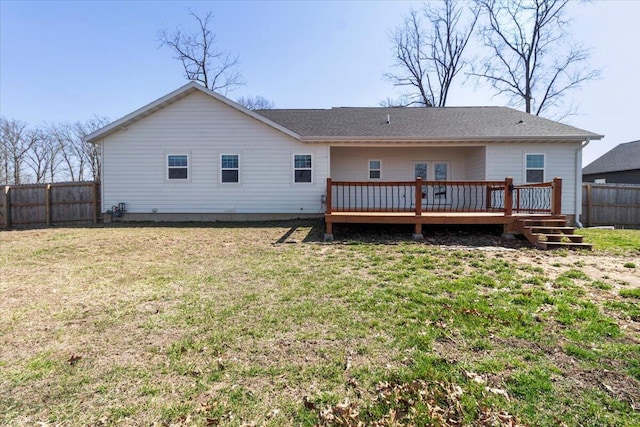 back of property featuring a yard, a wooden deck, a fenced backyard, and roof with shingles