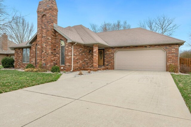 view of front of home featuring concrete driveway, a shingled roof, a garage, brick siding, and a chimney