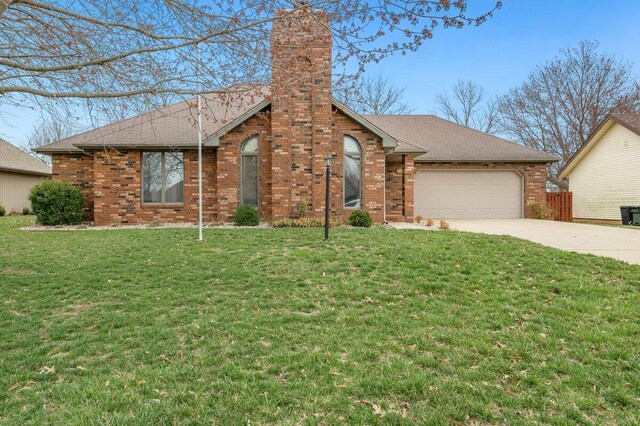 ranch-style home with driveway, a front yard, a garage, brick siding, and a chimney