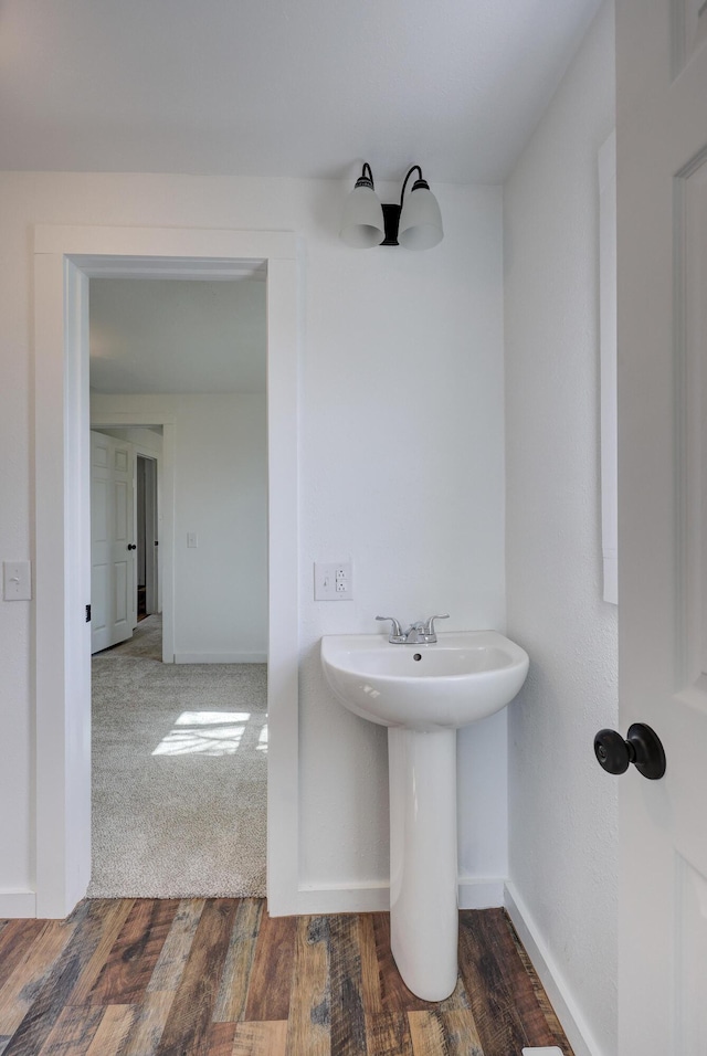 bathroom with wood finished floors, baseboards, and a sink