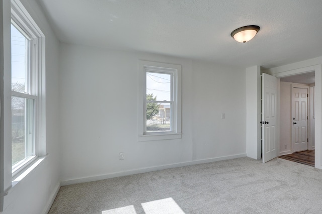 empty room featuring baseboards, carpet floors, and a textured ceiling