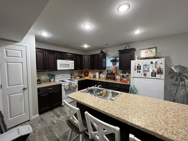 610 N Center St, Willow Springs, MO 65793 - kitchen featuring a sink, a kitchen breakfast bar, wood finished floors, white appliances, and light countertops