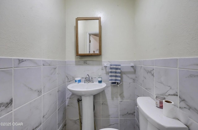 half bathroom with a sink, toilet, and a textured wall