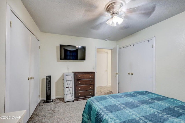 bedroom with baseboards, ceiling fan, light colored carpet, a closet, and a textured ceiling