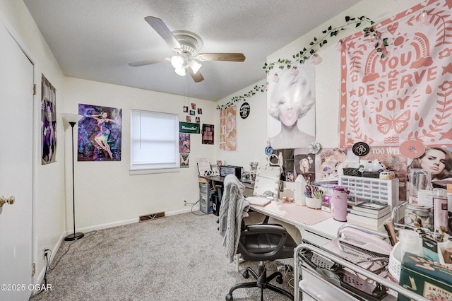 carpeted home office with baseboards, visible vents, a textured ceiling, and ceiling fan