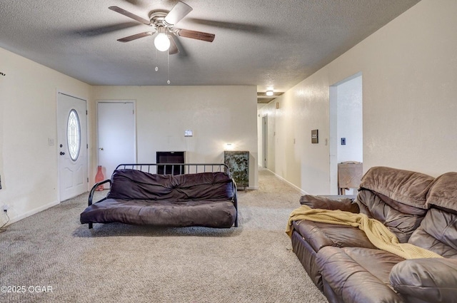 living area with baseboards, ceiling fan, a textured ceiling, and carpet