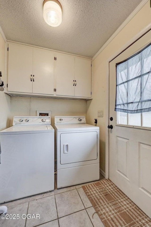 laundry room with washing machine and clothes dryer, light tile patterned floors, cabinet space, and a textured ceiling