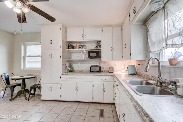 kitchen featuring white cabinetry, a ceiling fan, black microwave, and a sink