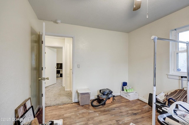 interior space featuring baseboards, a textured ceiling, ceiling fan, and wood finished floors