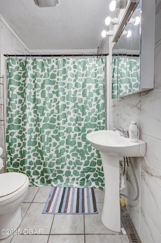 bathroom featuring a shower with shower curtain, a textured ceiling, tile patterned flooring, and toilet