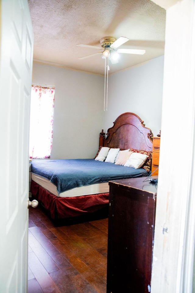 bedroom with a textured ceiling, ceiling fan, and hardwood / wood-style flooring