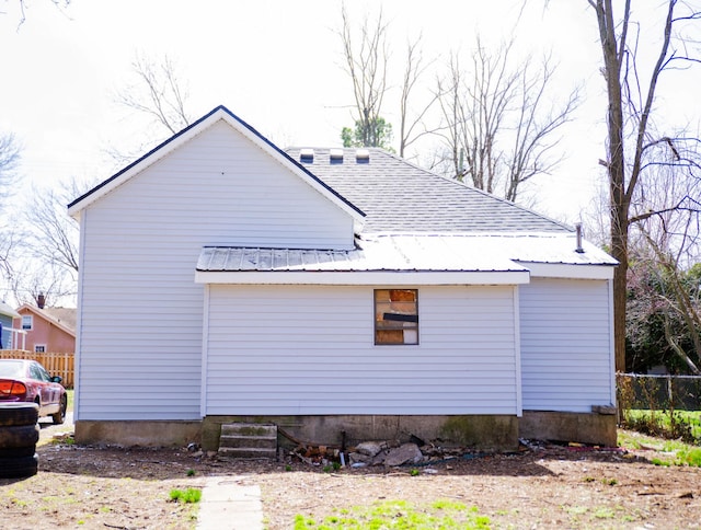 view of side of home featuring fence and metal roof