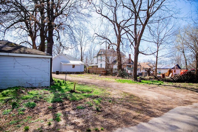 view of yard featuring fence, a residential view, and driveway