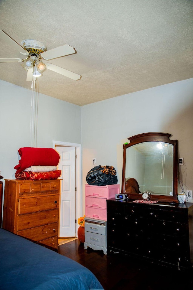 bedroom with ceiling fan, wood finished floors, and a textured ceiling
