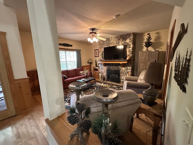 215 Oakridge Rd, Branson, MO 65616 - living room featuring wood finished floors, ceiling fan, a stone fireplace, and wainscoting