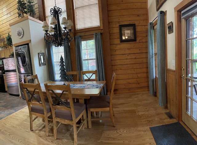 215 Oakridge Rd, Branson, MO 65616 - dining area with stacked washer and clothes dryer, a chandelier, wood walls, plenty of natural light, and light wood-type flooring