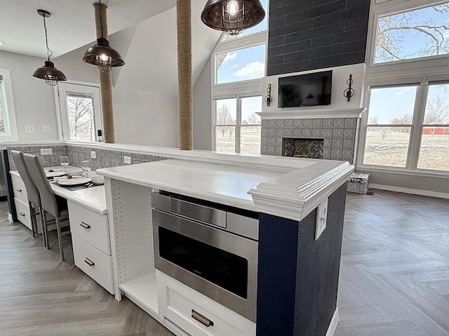 3100 E 354th Rd, El Dorado Springs, MO 64744 - kitchen with white cabinetry, decorative light fixtures, light countertops, and a tiled fireplace
