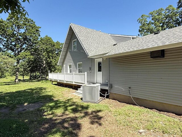 3100 E 354th Rd, El Dorado Springs, MO 64744 - back of house with central air condition unit, a yard, roof with shingles, and a wooden deck