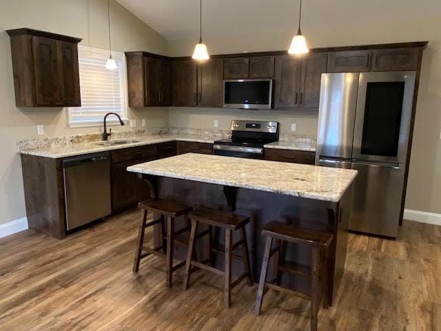 2520 S Schifferdecker Ave, Joplin, MO 64804 - kitchen featuring dark brown cabinets, a center island, appliances with stainless steel finishes, wood finished floors, and a sink