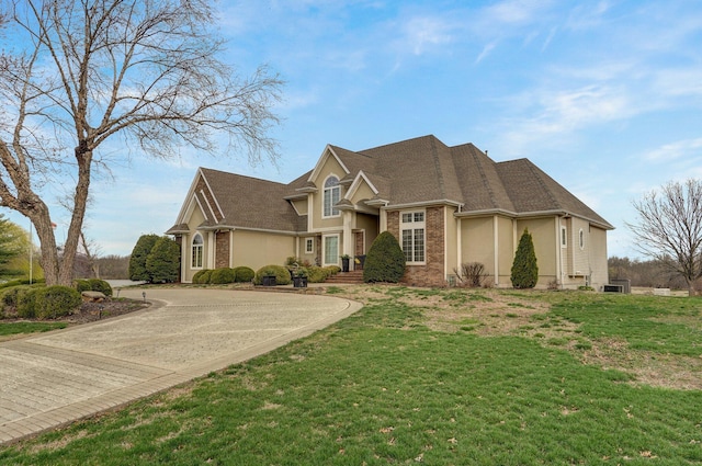 304 Reavley Dr, Lamar, MO 64759 - view of front of property with a front yard, a shingled roof, stucco siding, curved driveway, and brick siding